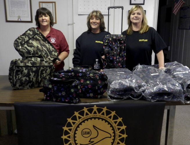Karen Foster, left, Angie Wymer, center, and Rosa Rankin, right, members of the Local United Auto Workers 2999 union, set up suitcases for children in the foster care program. Kaley Toy/Daily